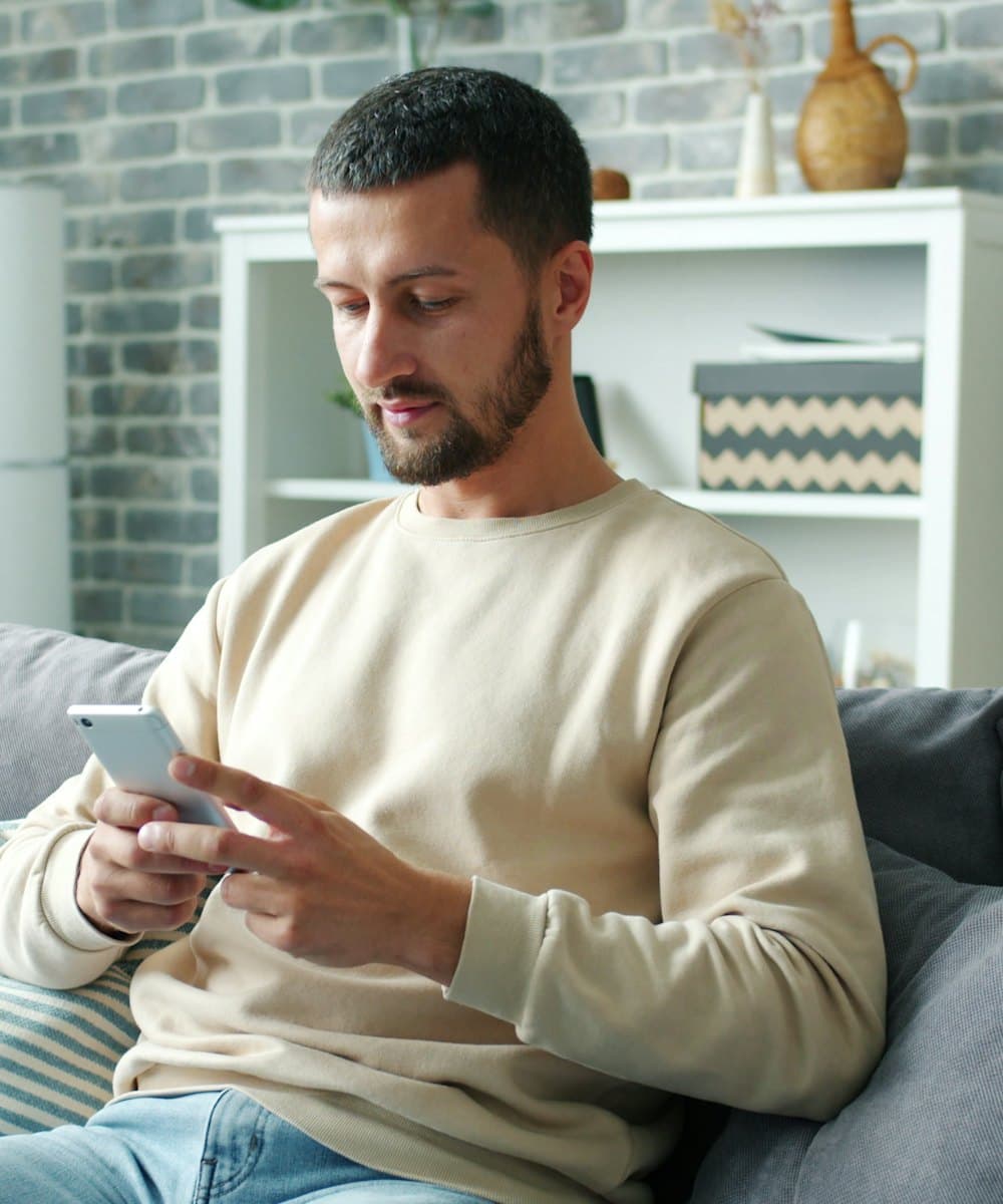 Un homme lance sa recherche depuis son téléphone, dans son salon